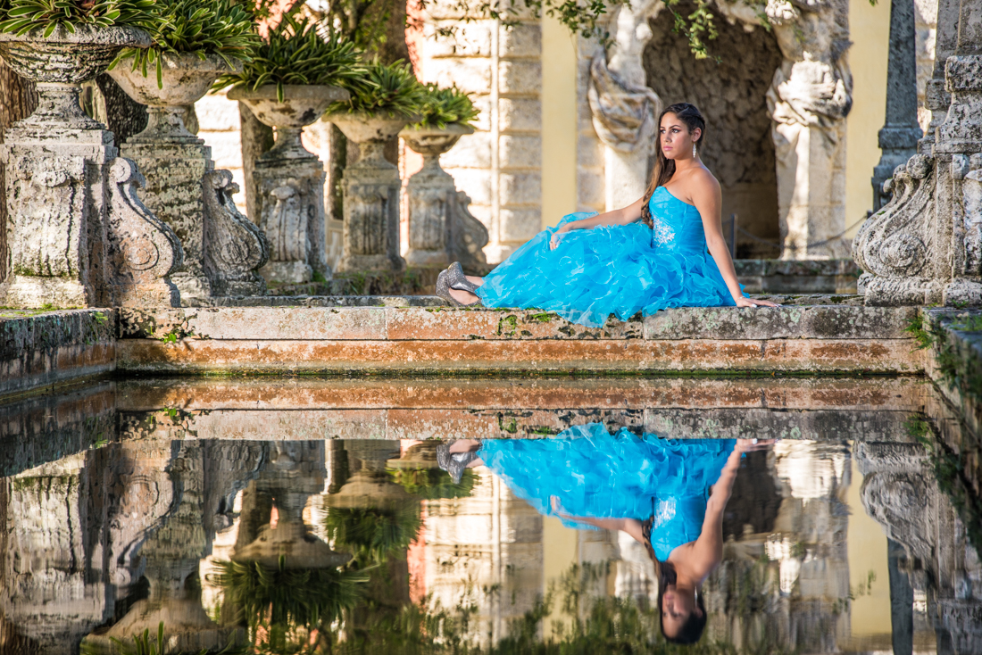 Quinceañera on blue dress reflecting on water at Vizcaya museum
